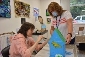 CSW supports a client painting her papier mache birdhouse
