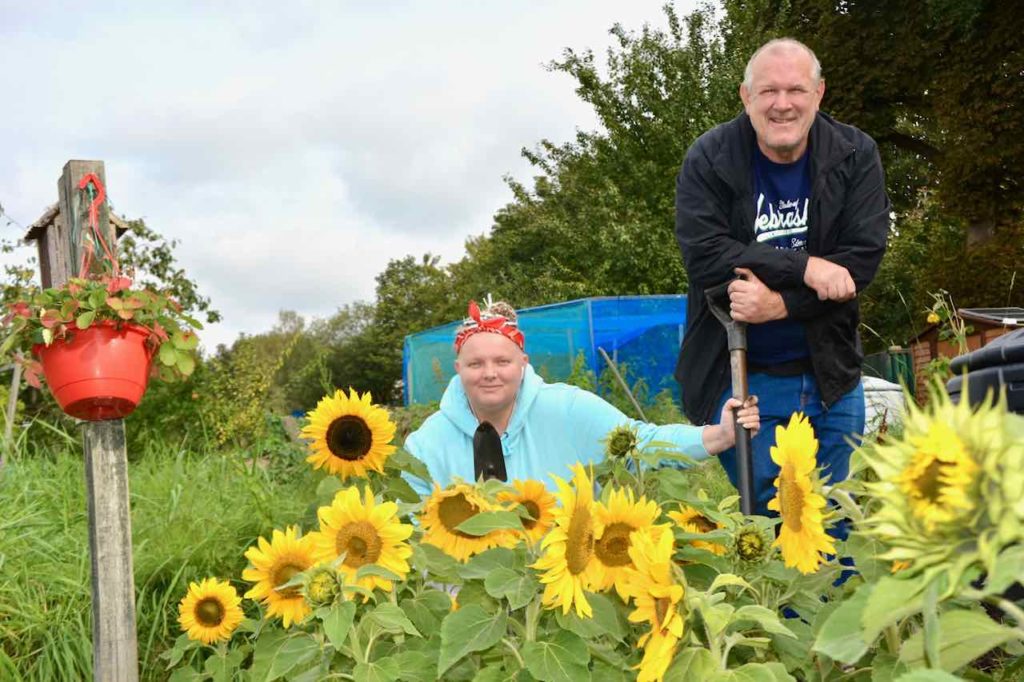 Our Social Impact Report is live! 21 Two MHN Mental Health Network cleints beside sunflowers grown at the allotment