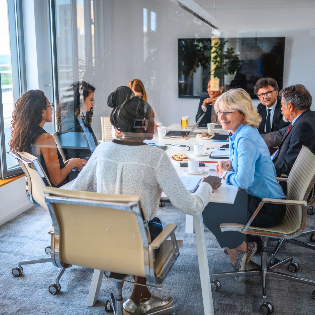 Our Story 7 Corporates sat round a table in office