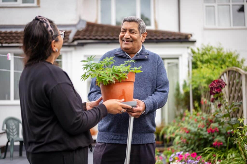 The Community Hub 10 Asian pensioner holding plant in garden with woman dressed in black