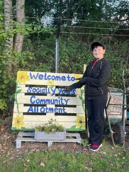 The Community Hub 12 Woman dressed in black stood in front of wooden pallet allotment