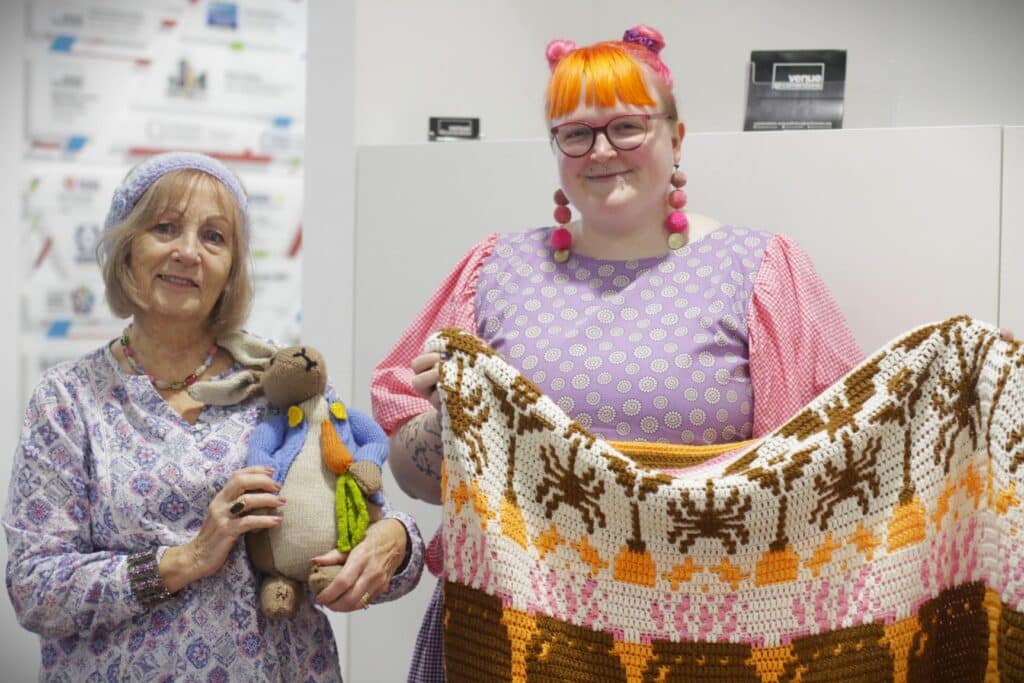 The Community Hub 11 Two women holding up knitted blanket and toy